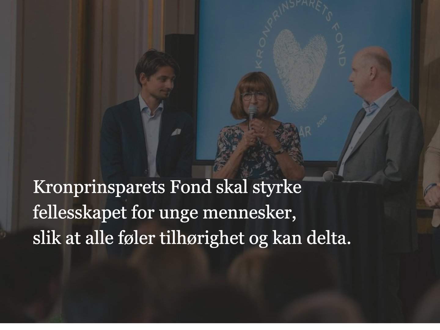 Utsnitt av forsiden til kronprinsparetsfond.no: sitatet «Kronprinsparets Fond skal styrke fellesskapet for unge mennesker, slik at alle føler tilhørighet og kan delta» over tre personer på en scene foran en skjerm med fondets hjertelogo.